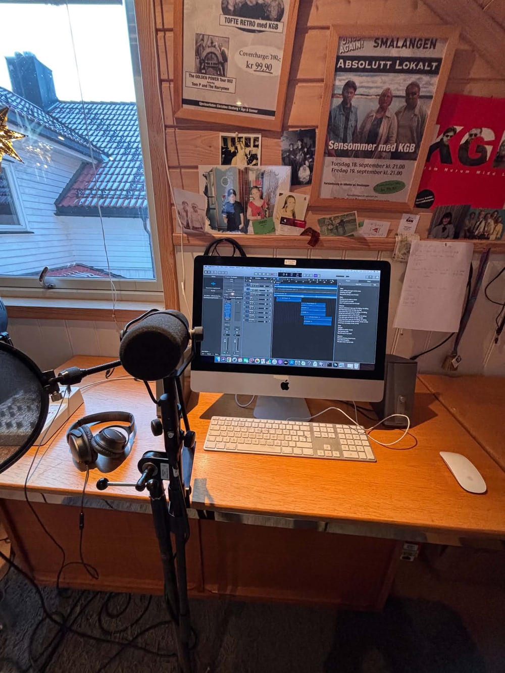Skrivebordet i studioet med lydprogram på skjermen, mikrofon og hodetelefoner.